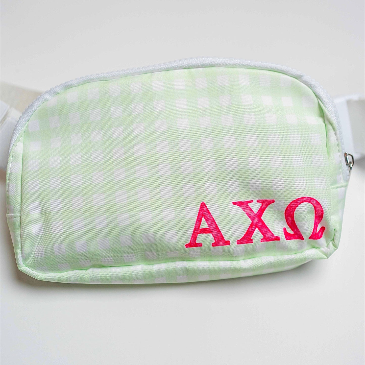 Green gingham pouch with pink Alpha Chi Omega Greek letters on a white background