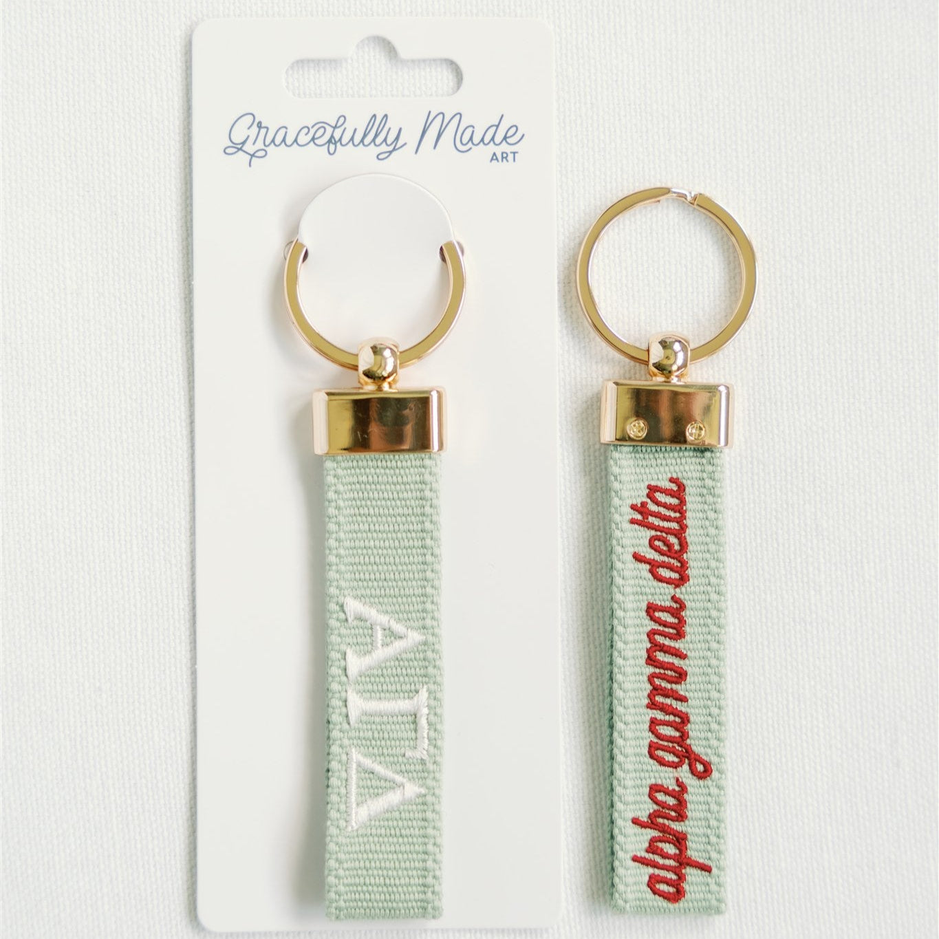 Front and back of Alpha Gamma Delta keychain with Gracefully Made Art branded packaging.