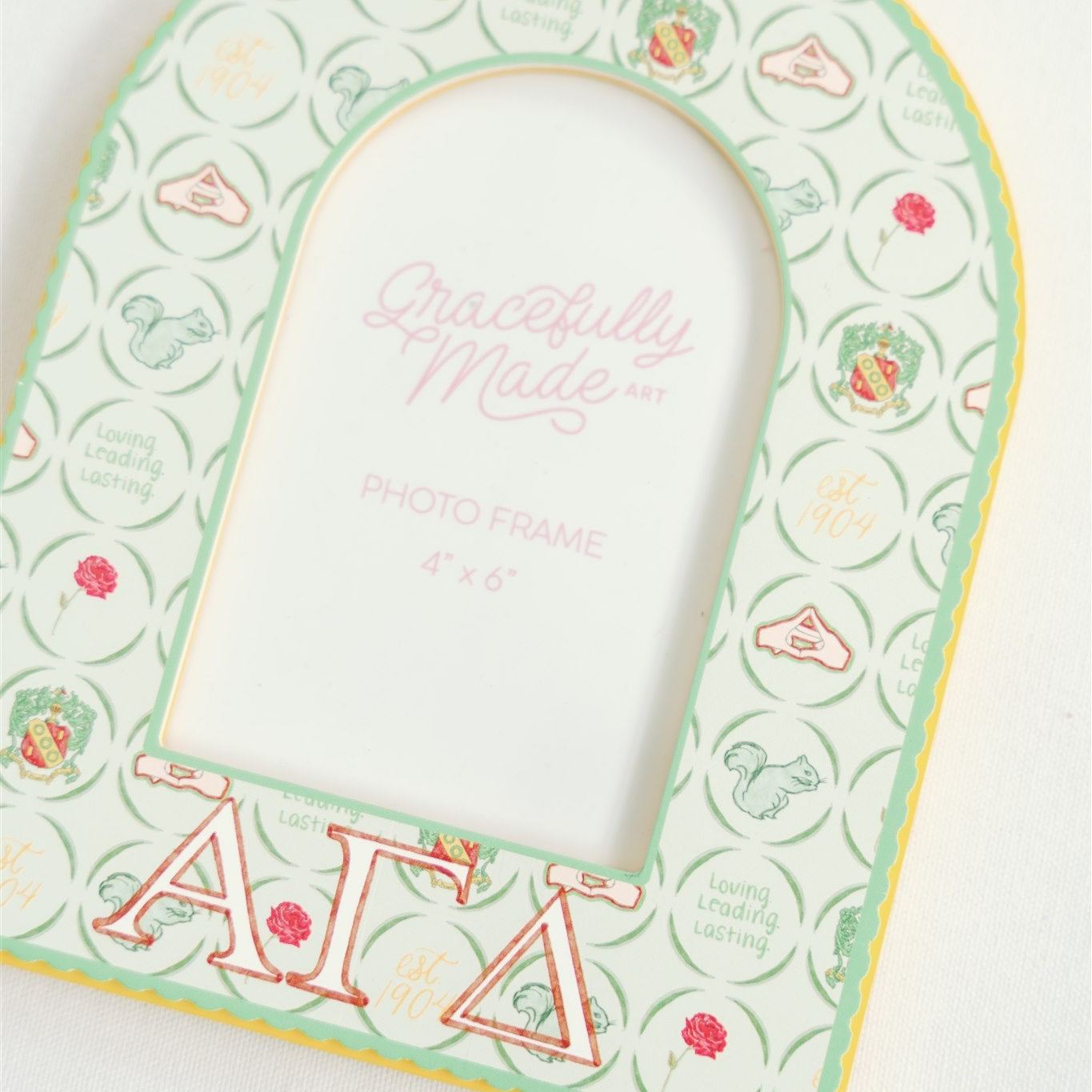 Close up of Alpha Gamma Delta picture frame with a watercolor pattern and Greek letters on the bottom of the frame.