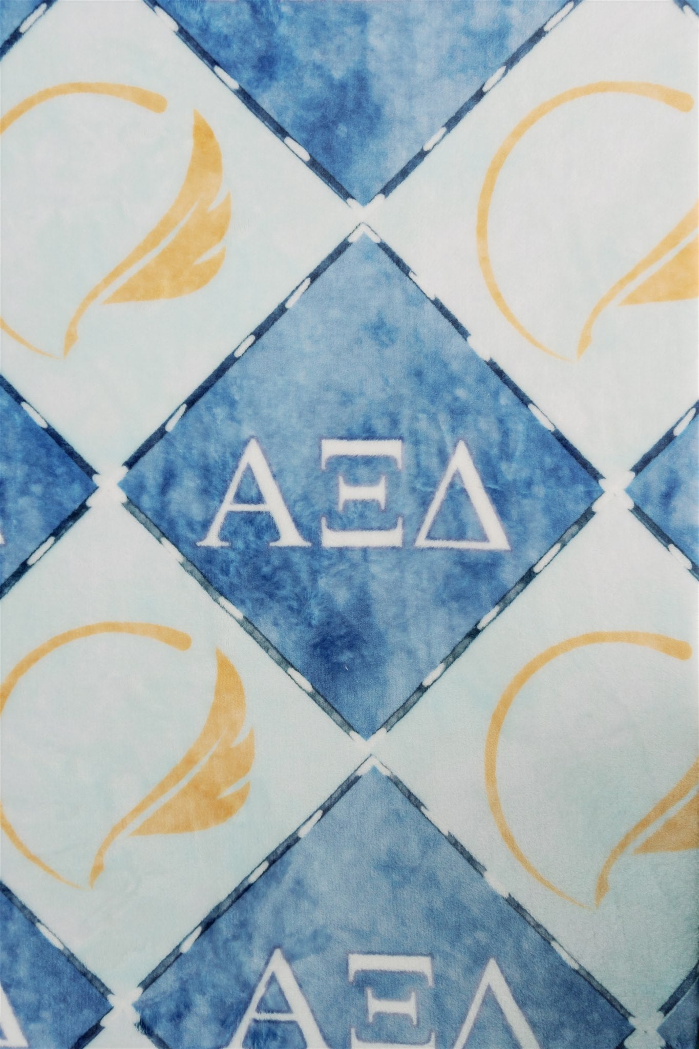 Patterned fabric with blue and gold design featuring Greek letters for Alpha Xi Delta sorority
