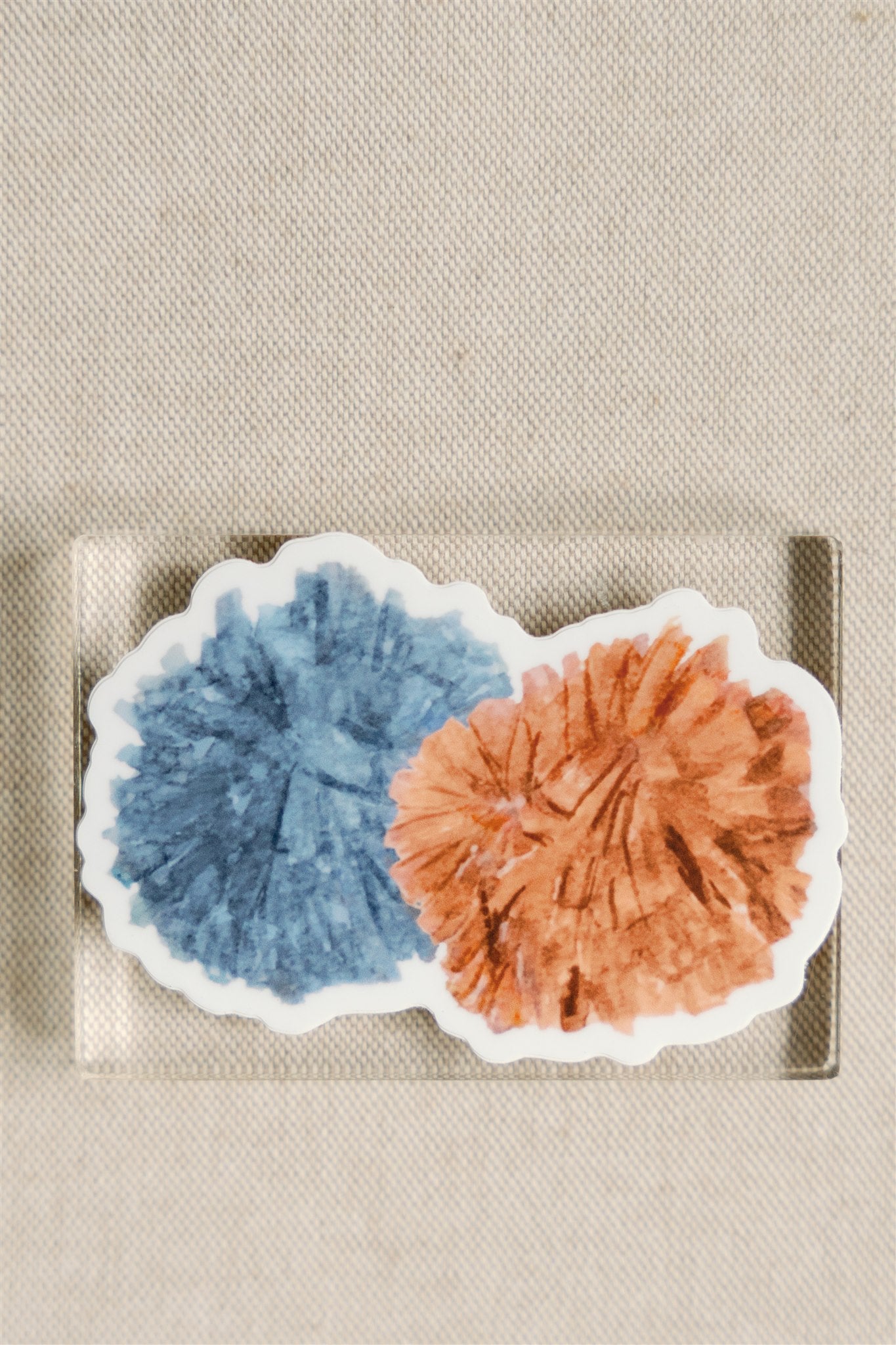Sticker of an orange and blue pom pom.