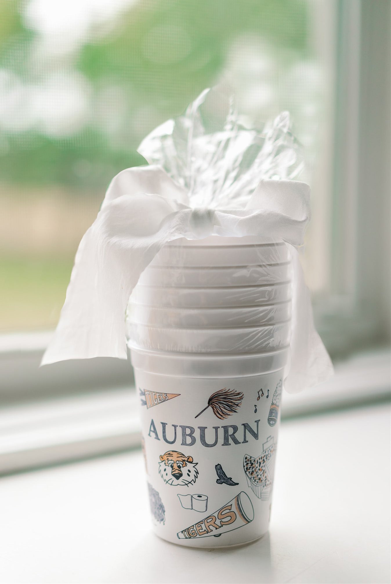 White plastic cups showcasing watercolor illustrations of popular Auburn landmarks & icons.