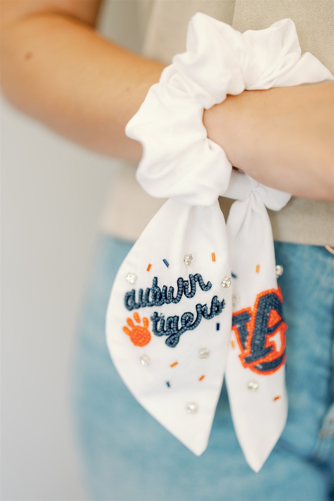 White scrunchie with two ribbons featuring beading of the Auburn logo and "Auburn Tigers."