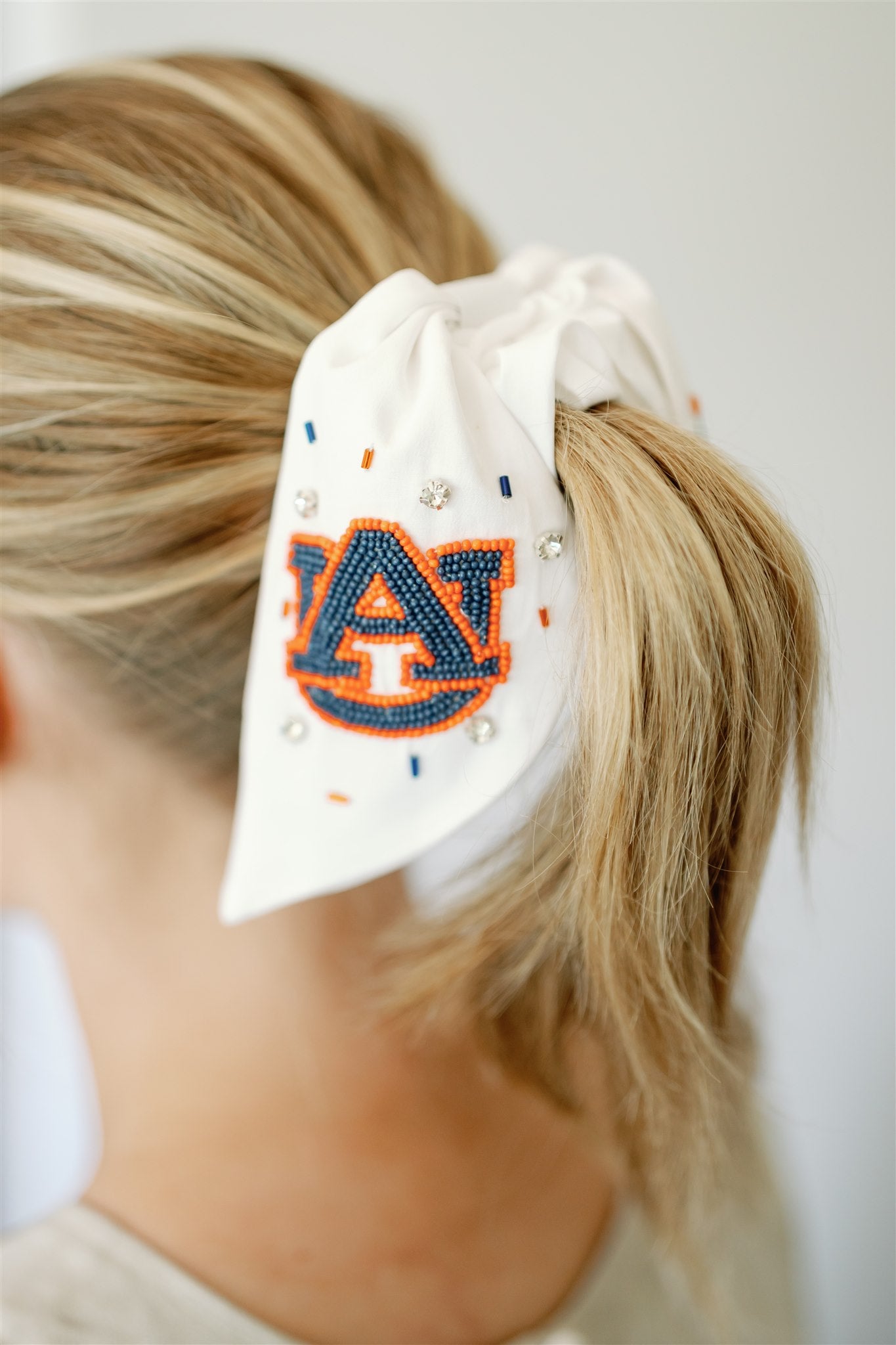 White scrunchie with two ribbons featuring beading of the Auburn logo and "Auburn Tigers."