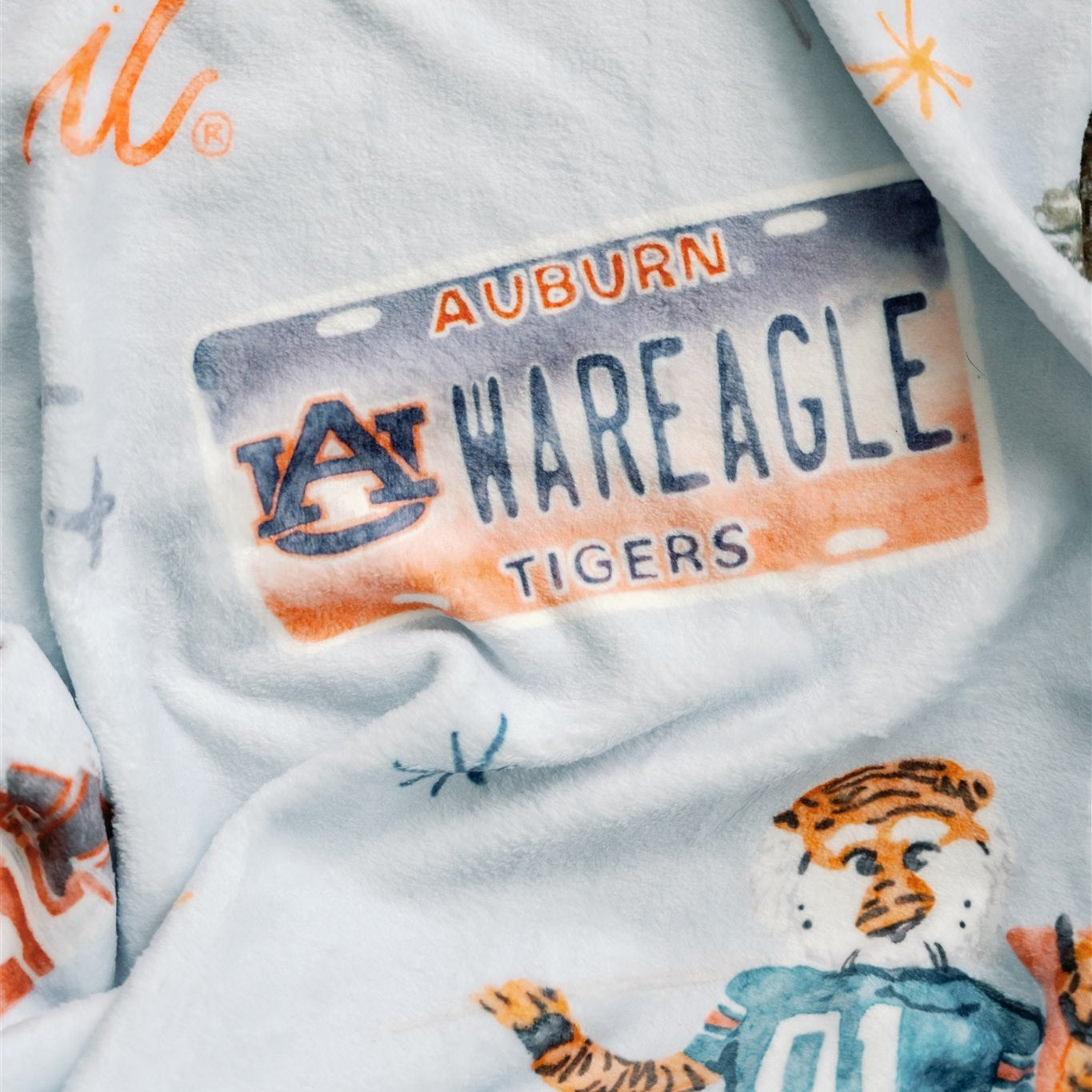 Light blue fleece blanket with watercolor Auburn University symbols.