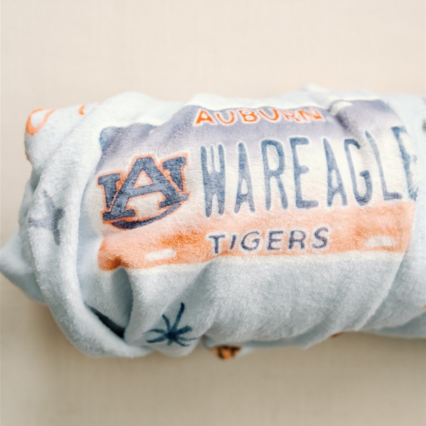 Light blue fleece blanket with watercolor Auburn University symbols.