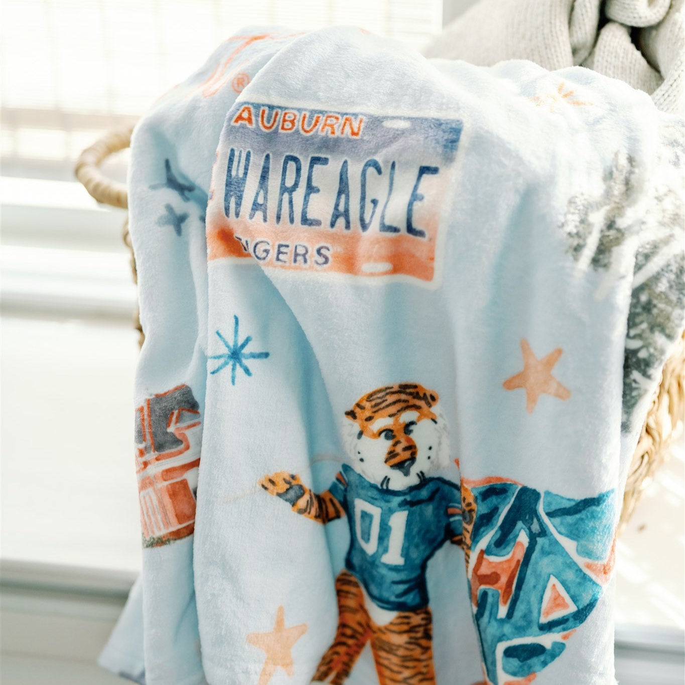 Light blue fleece blanket with watercolor Auburn University symbols.