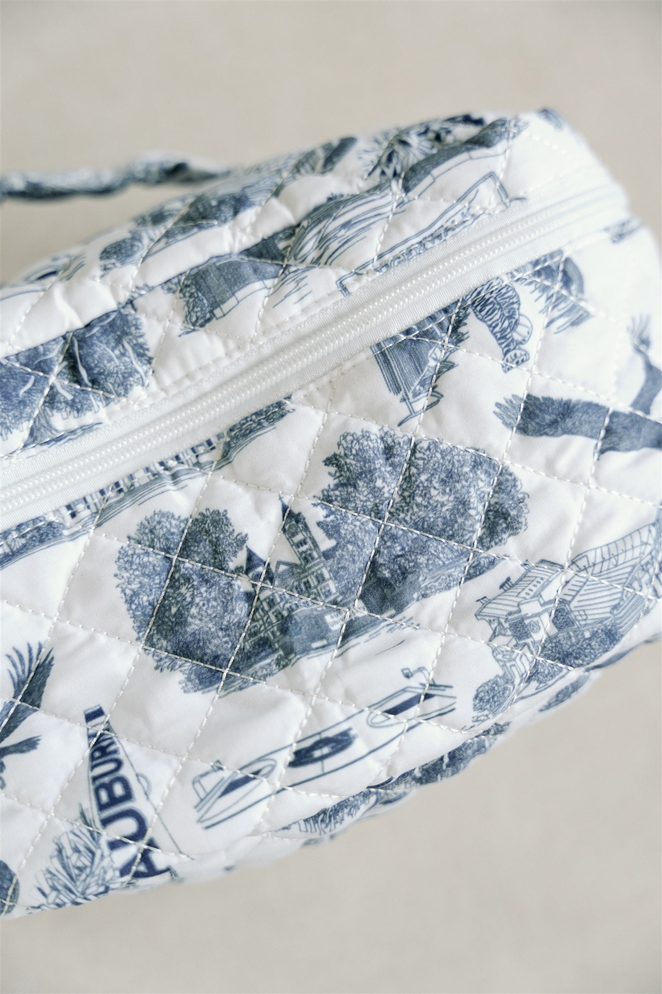White quilted makeup bag with navy blue Auburn University symbols.