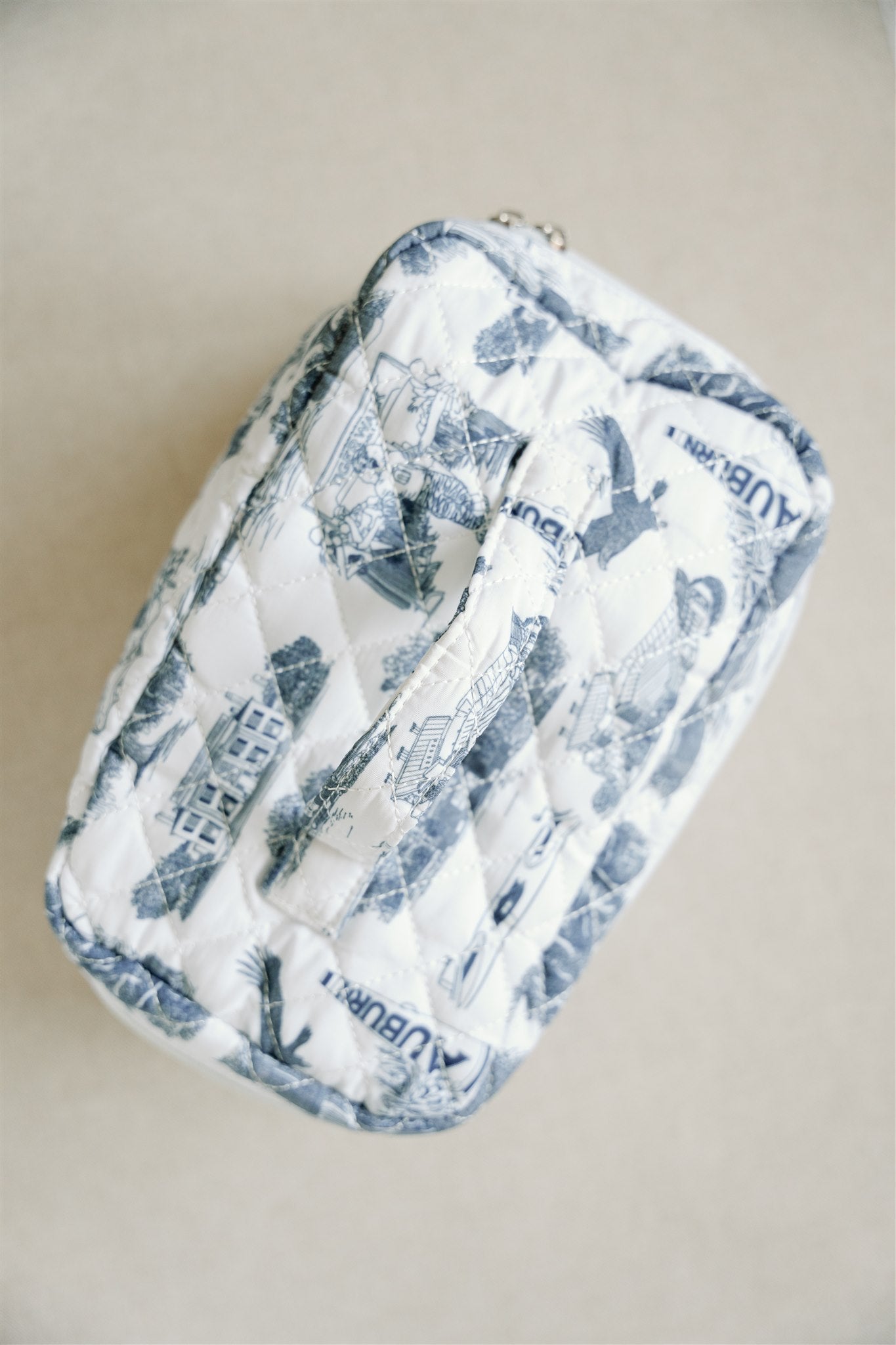 White quilted makeup bag with navy blue Auburn University symbols.