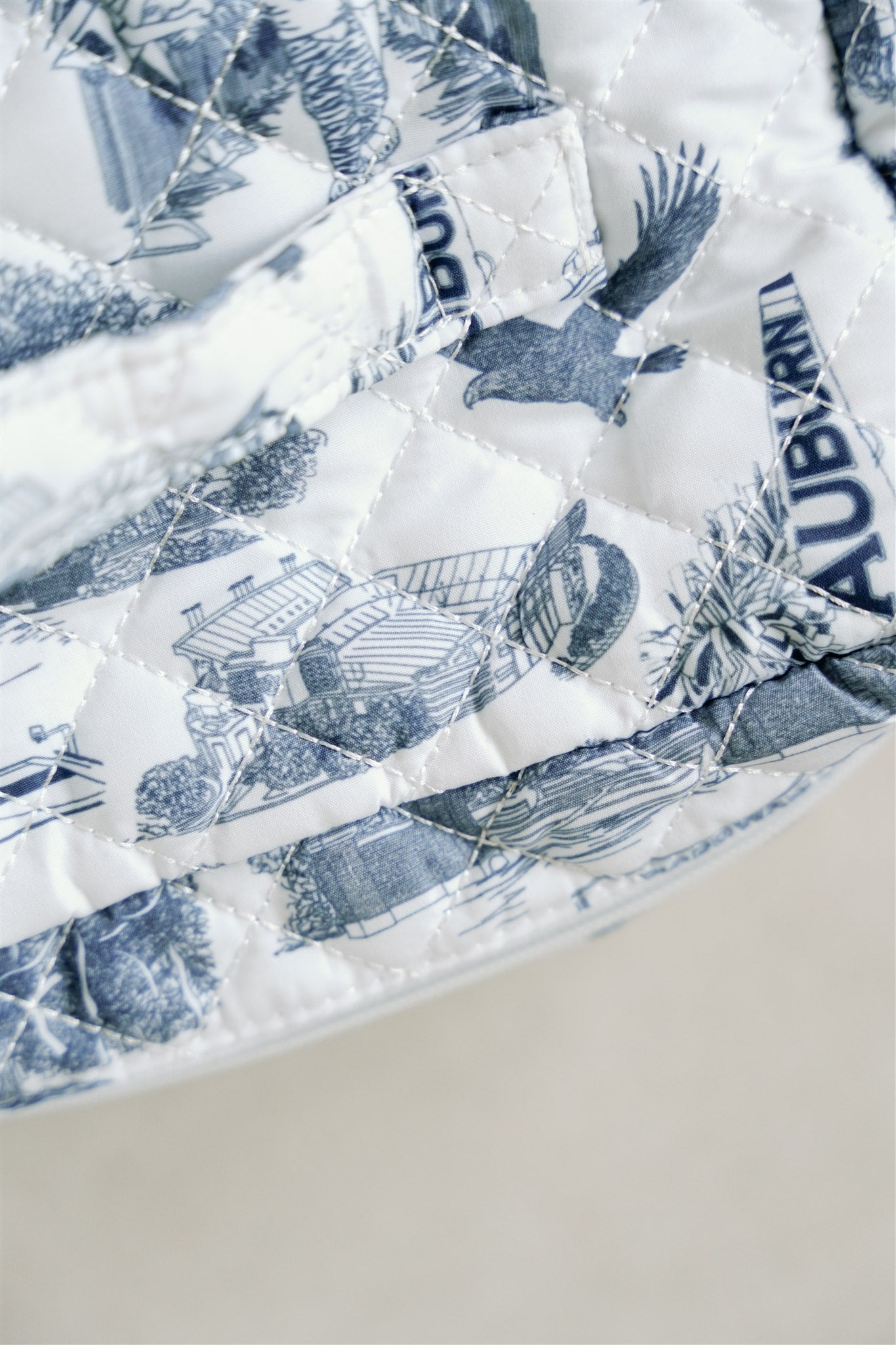 White quilted makeup bag with navy blue Auburn University symbols.