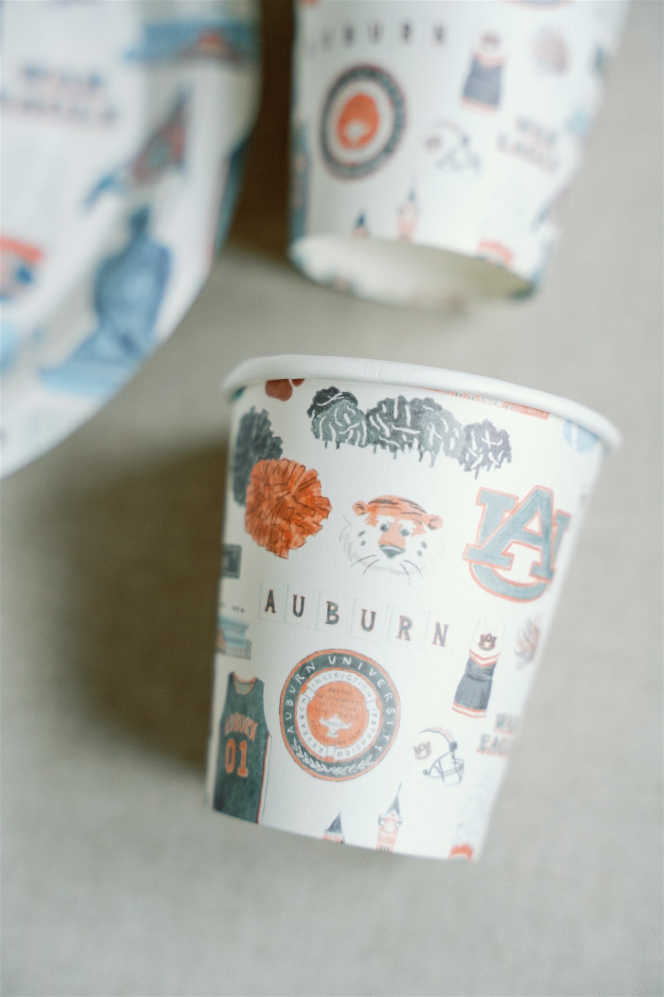 Paper cups with watercolor Auburn University icons and landmarks on them.