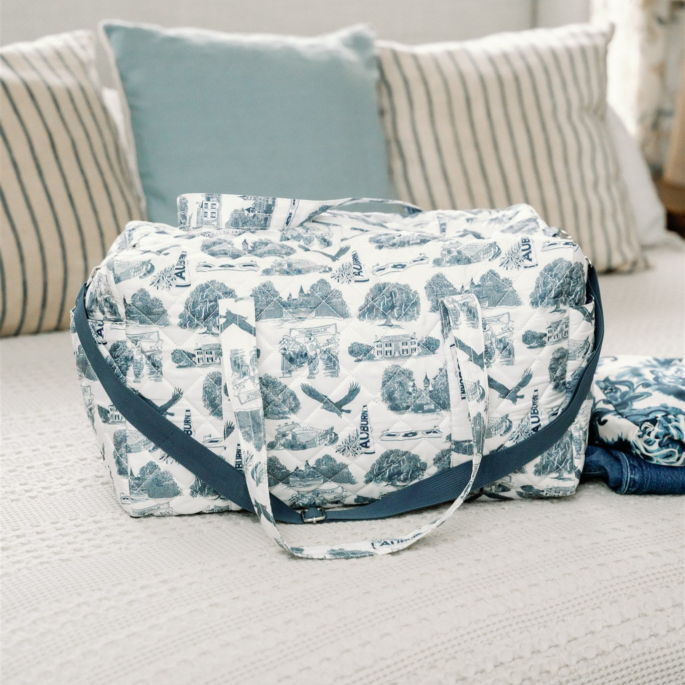 White quilted duffle bag with a navy strap and navy Auburn symbols.