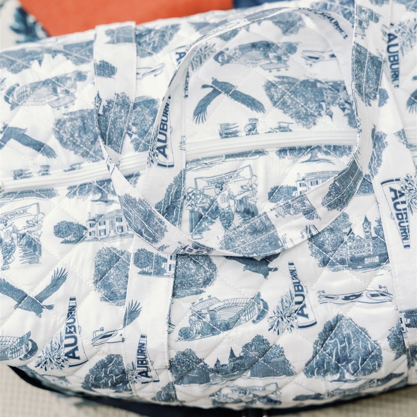 White quilted duffle bag with a navy strap and navy Auburn symbols.