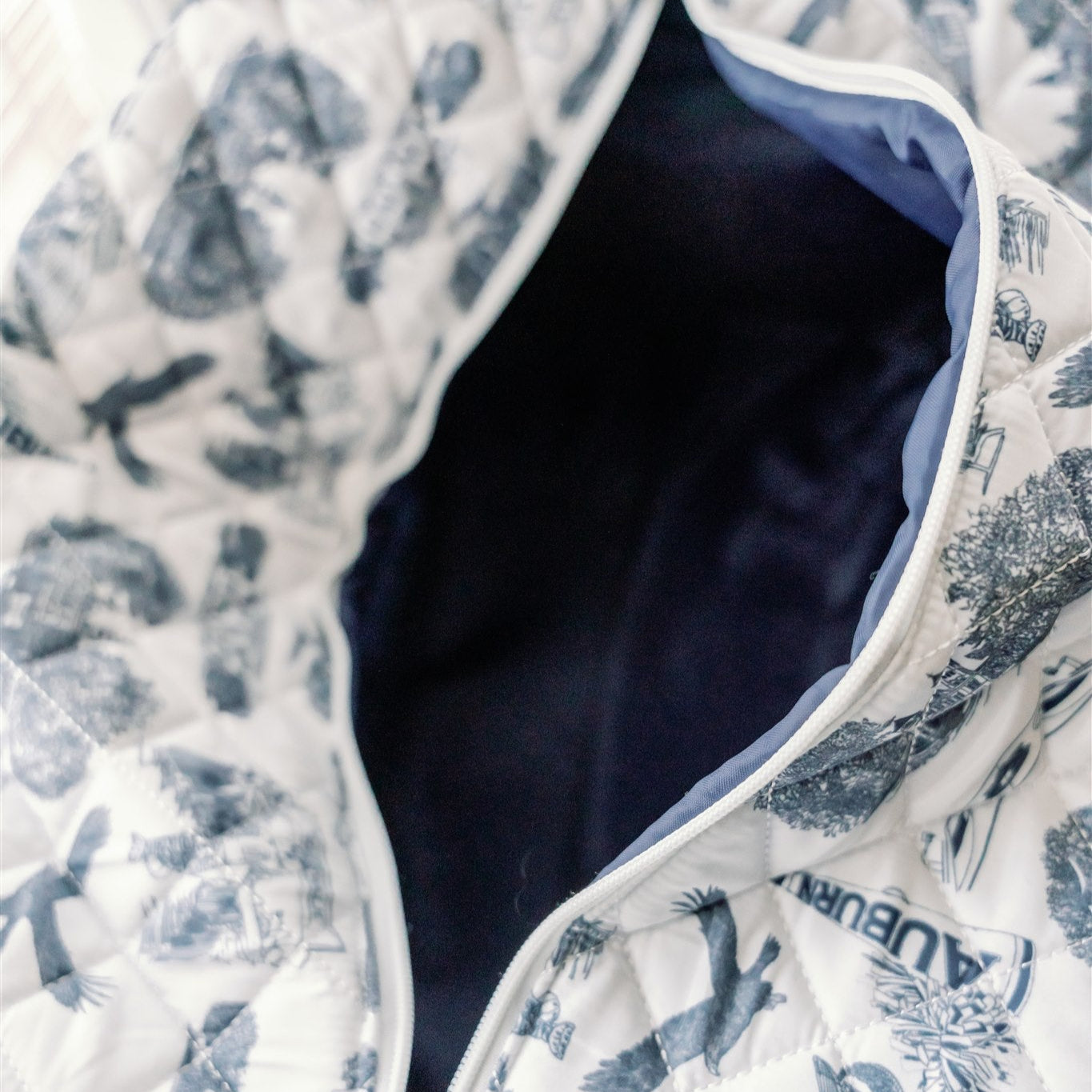 White quilted duffle bag with a navy strap and navy Auburn symbols.