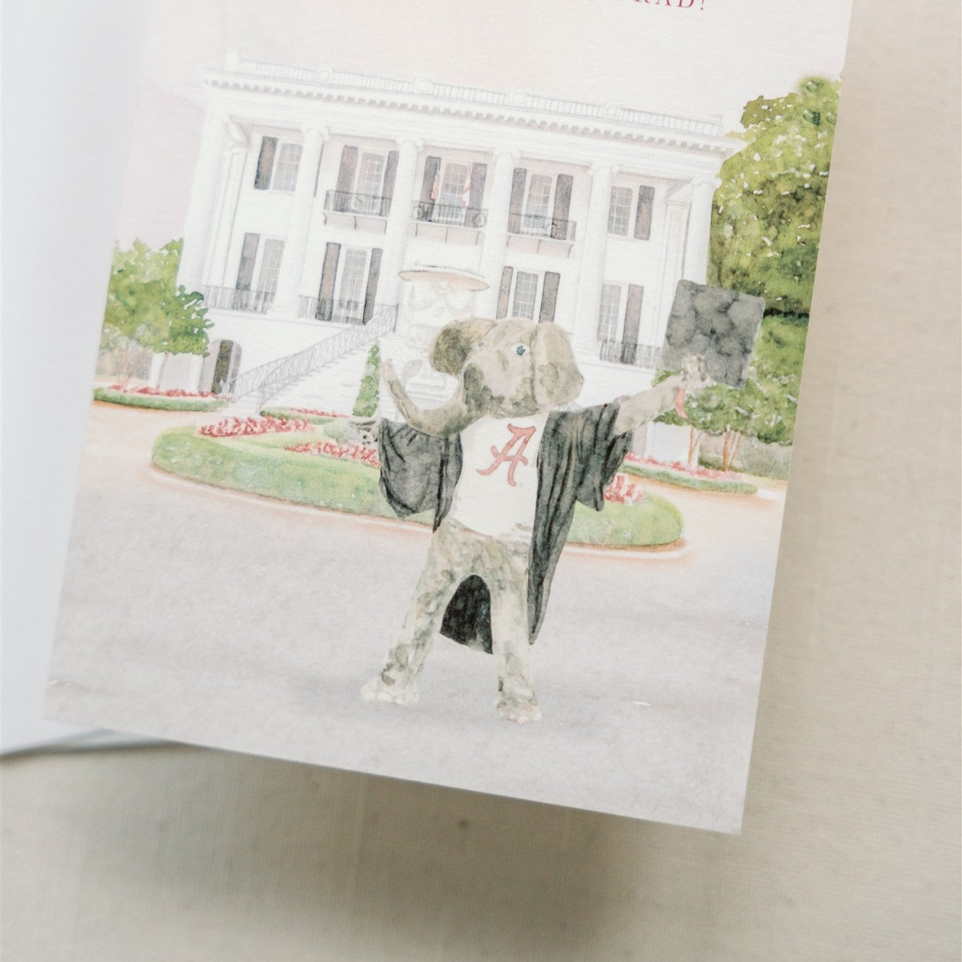 Watercolor card of the University of Alabama mascot, Big Al, in a graduation cap and gown.