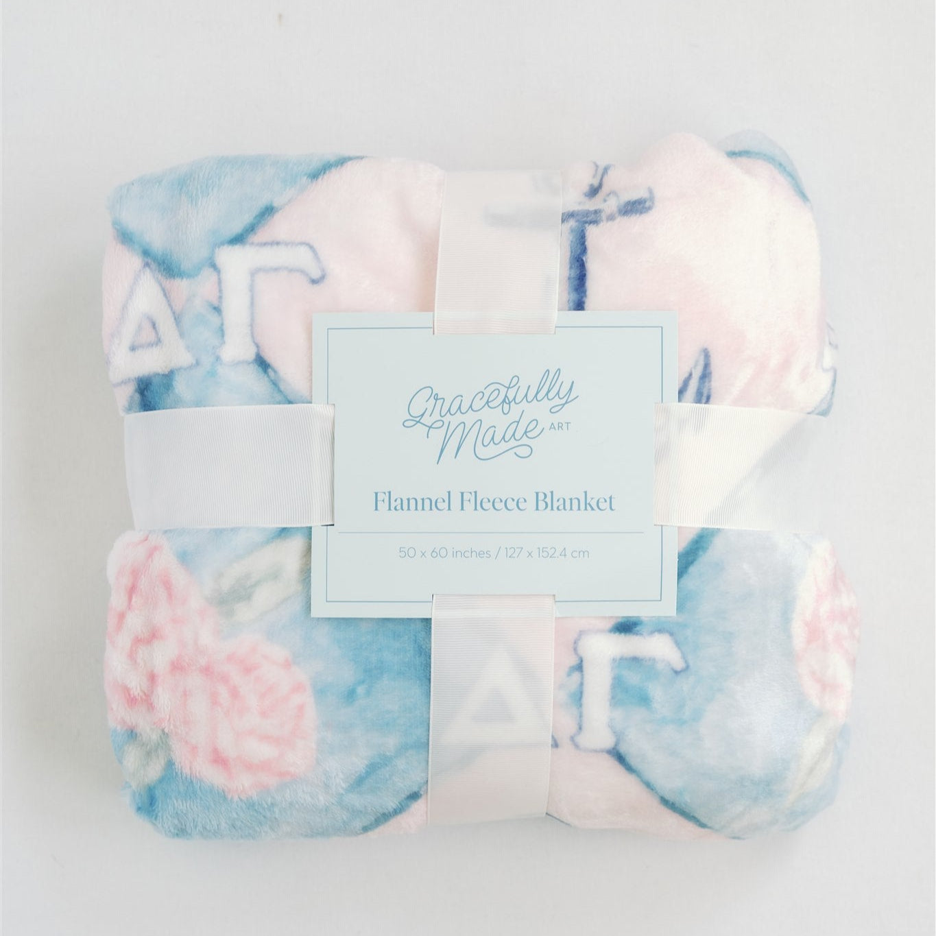 Flannel fleece blanket with floral pattern and brand label on a light gray background