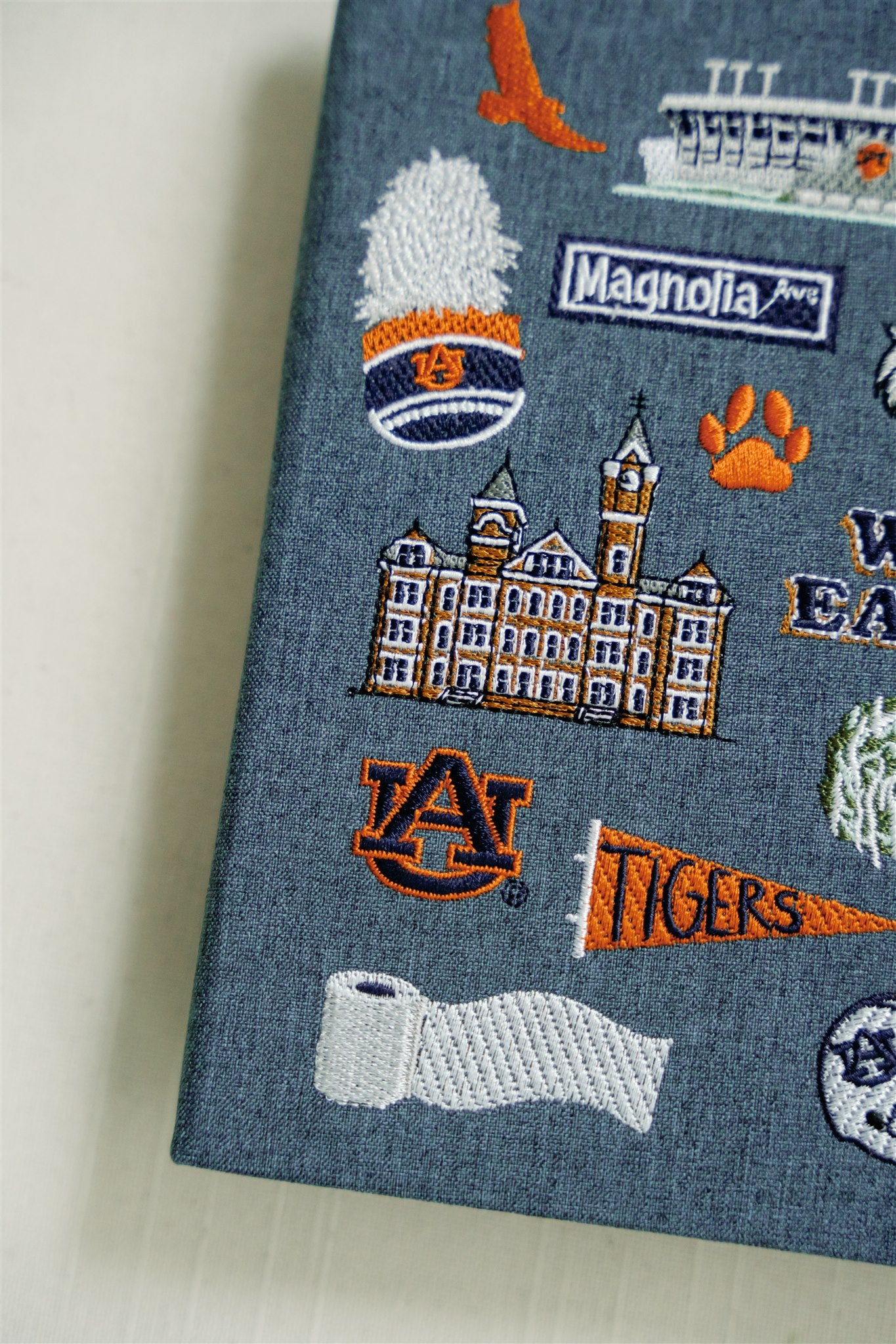 Hardcover navy blue notebook with various Auburn University icons embroidered on the front.