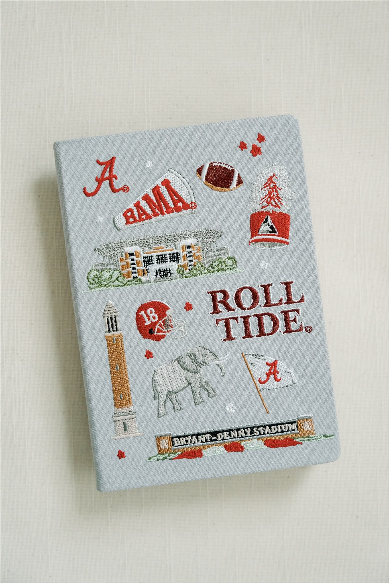 Light grey hardcover notebook with embroidered University of Alabama symbols on the front.