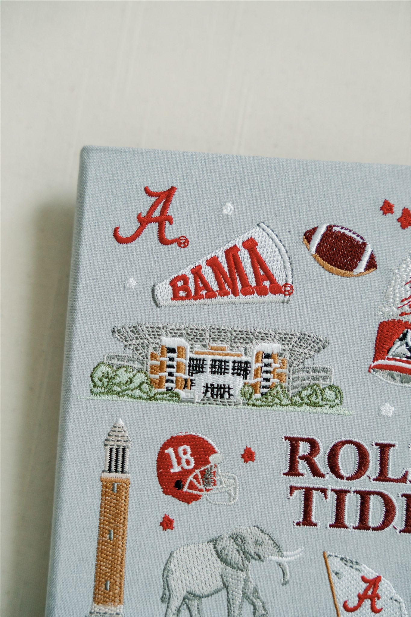 Light grey hardcover notebook with embroidered University of Alabama symbols on the front.