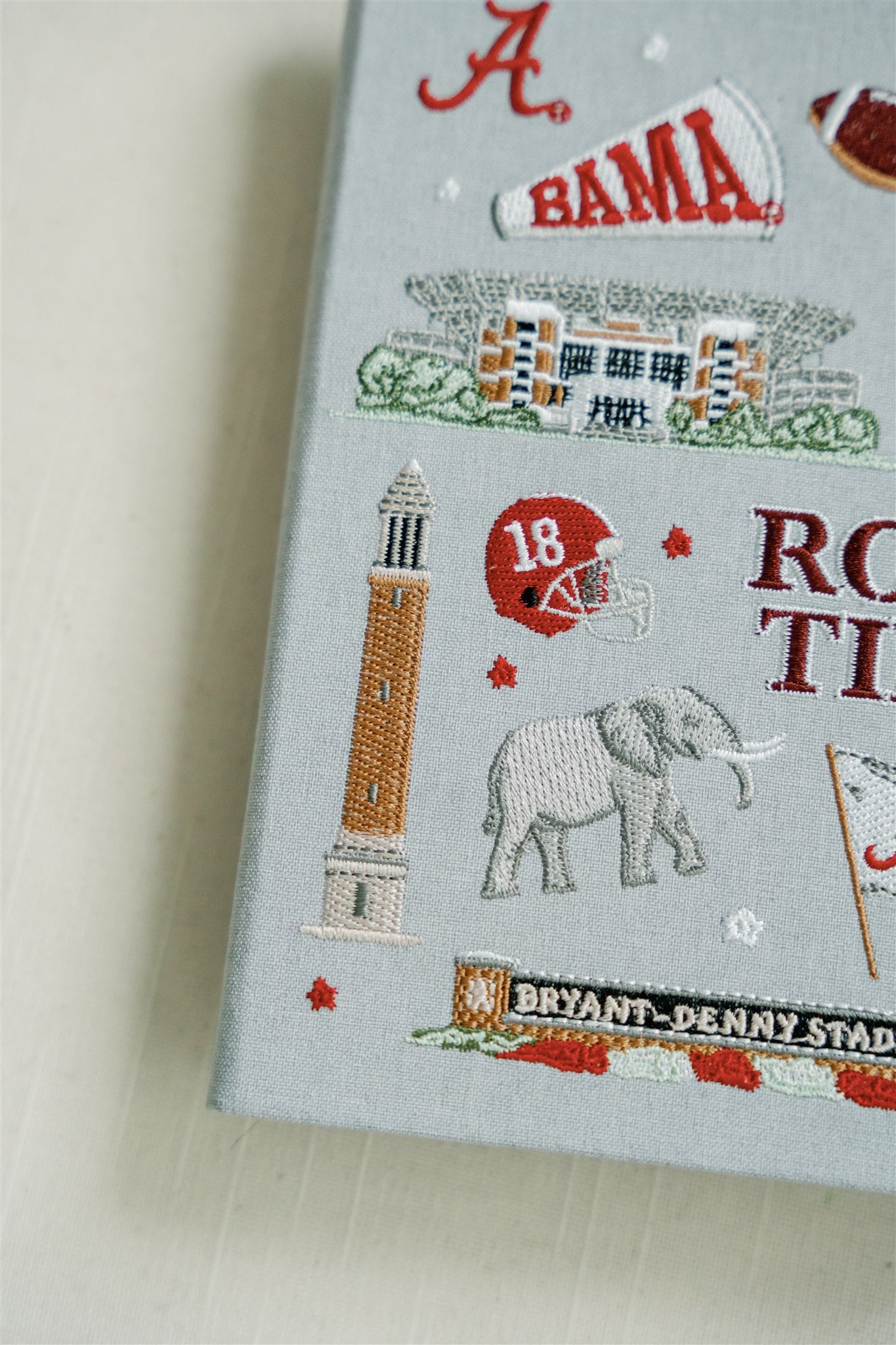 Light grey hardcover notebook with embroidered University of Alabama symbols on the front.