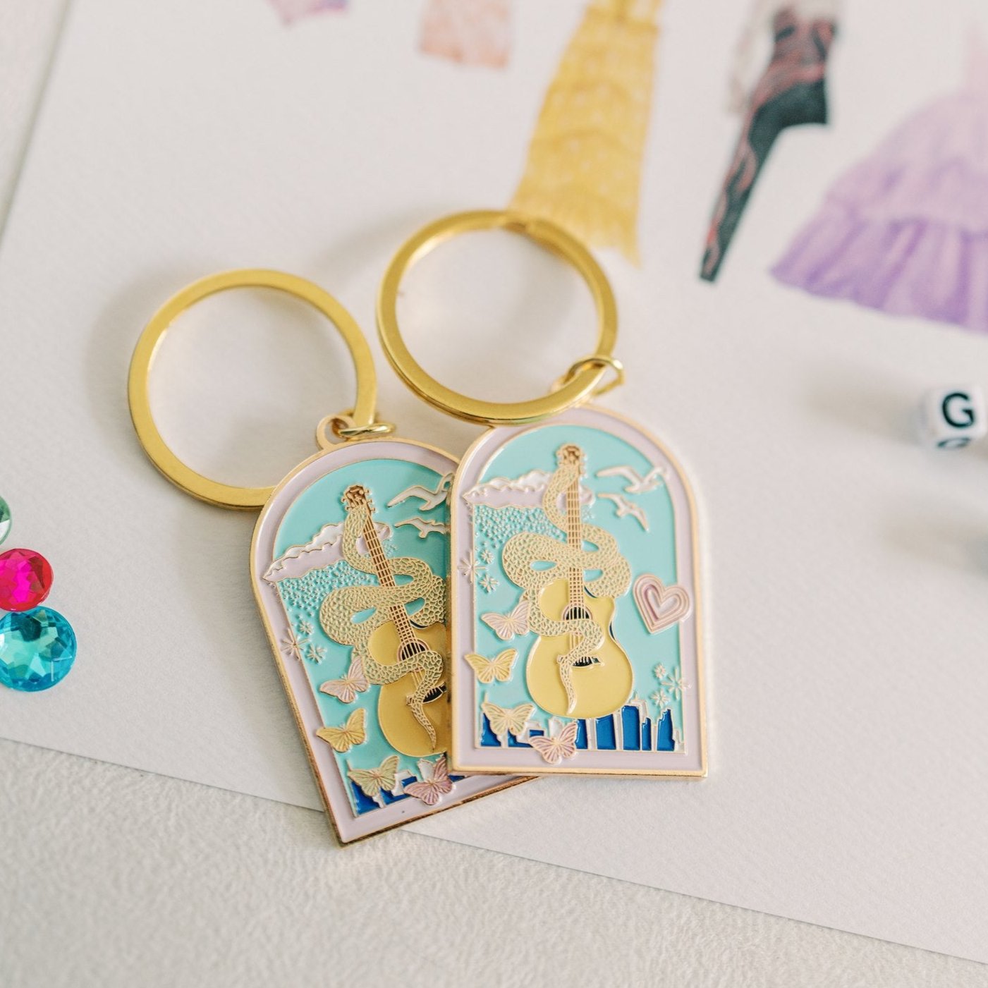 Enamel keychain with a gold loop and a guitar with a snake wrapped around it and the New York skyline in the background.