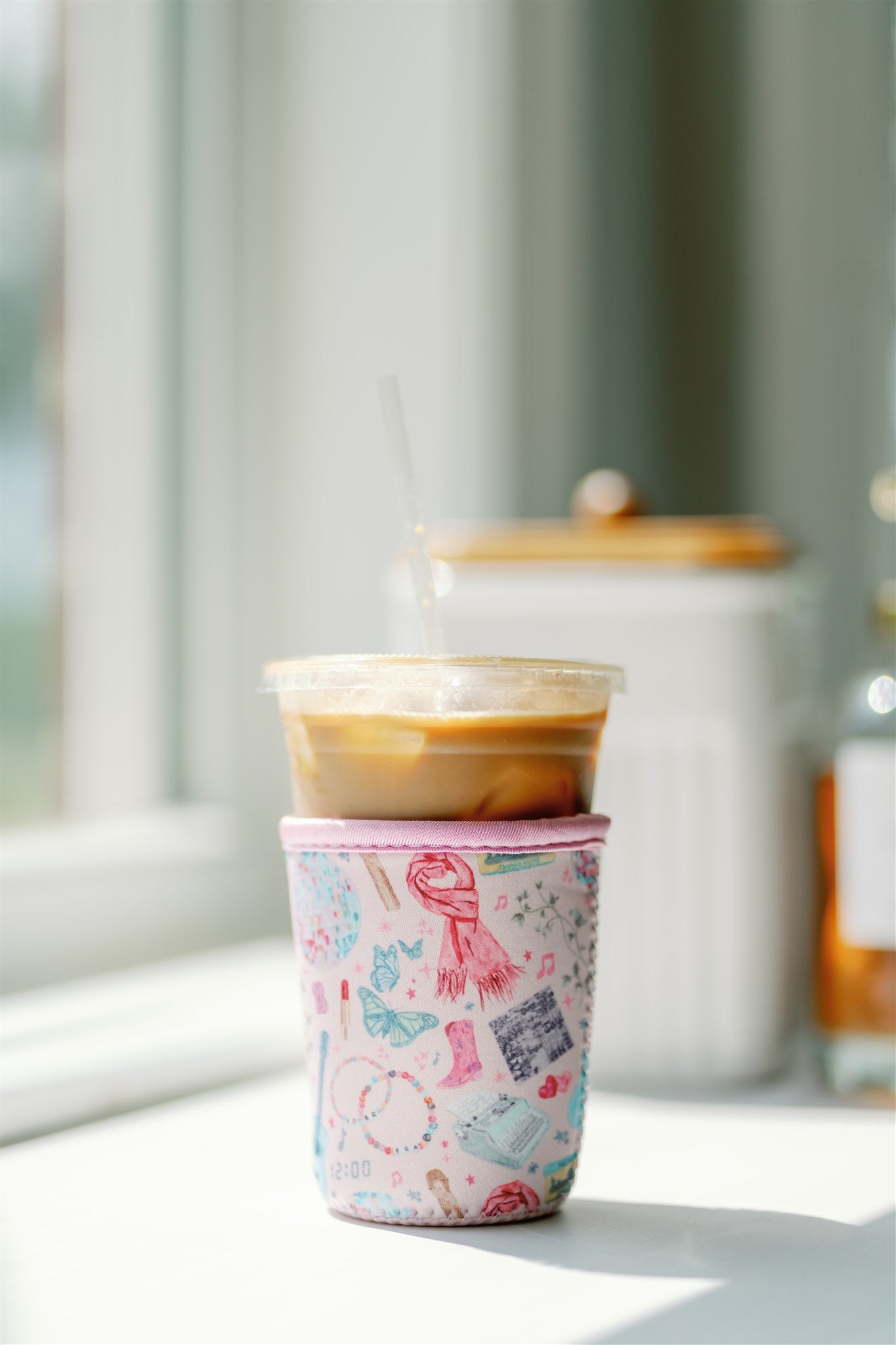 Light pink coffee sleeve with watercolor Taylor Swift inspired symbols.