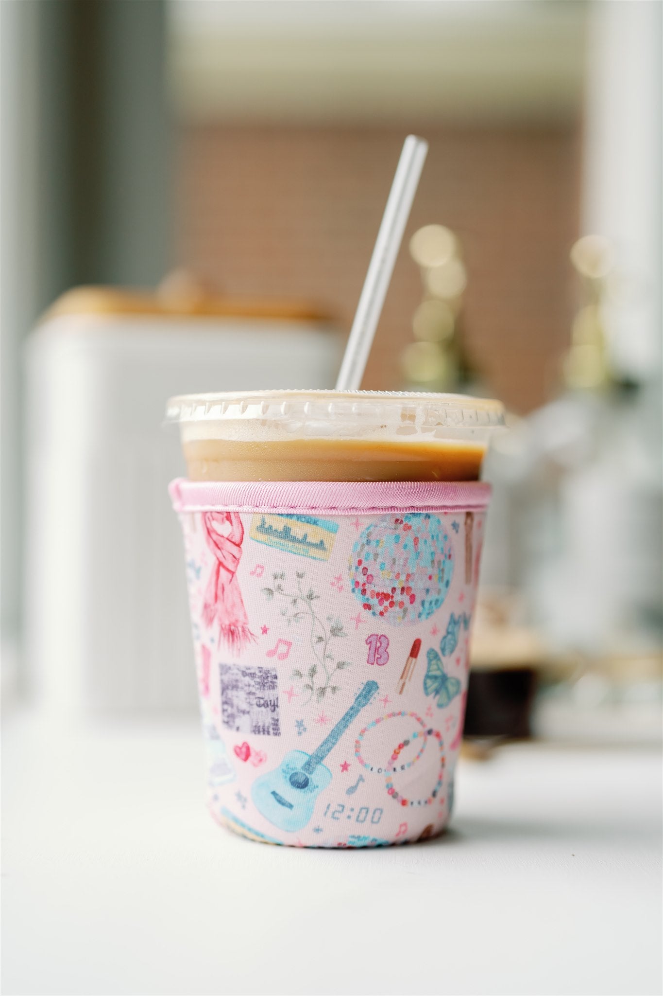 Light pink coffee sleeve with watercolor Taylor Swift inspired symbols.