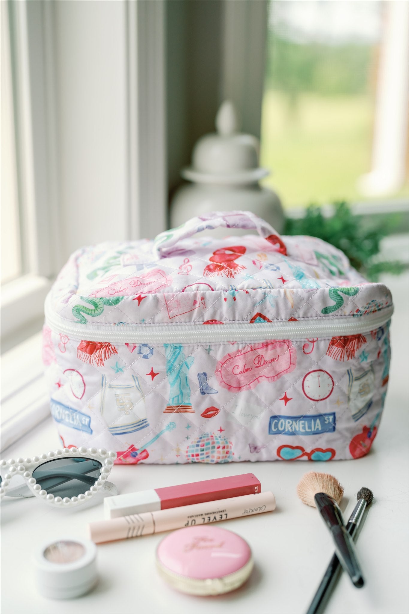 Quilted makeup bag with a pattern featuring original watercolor illustrations of Taylor Swift icons.