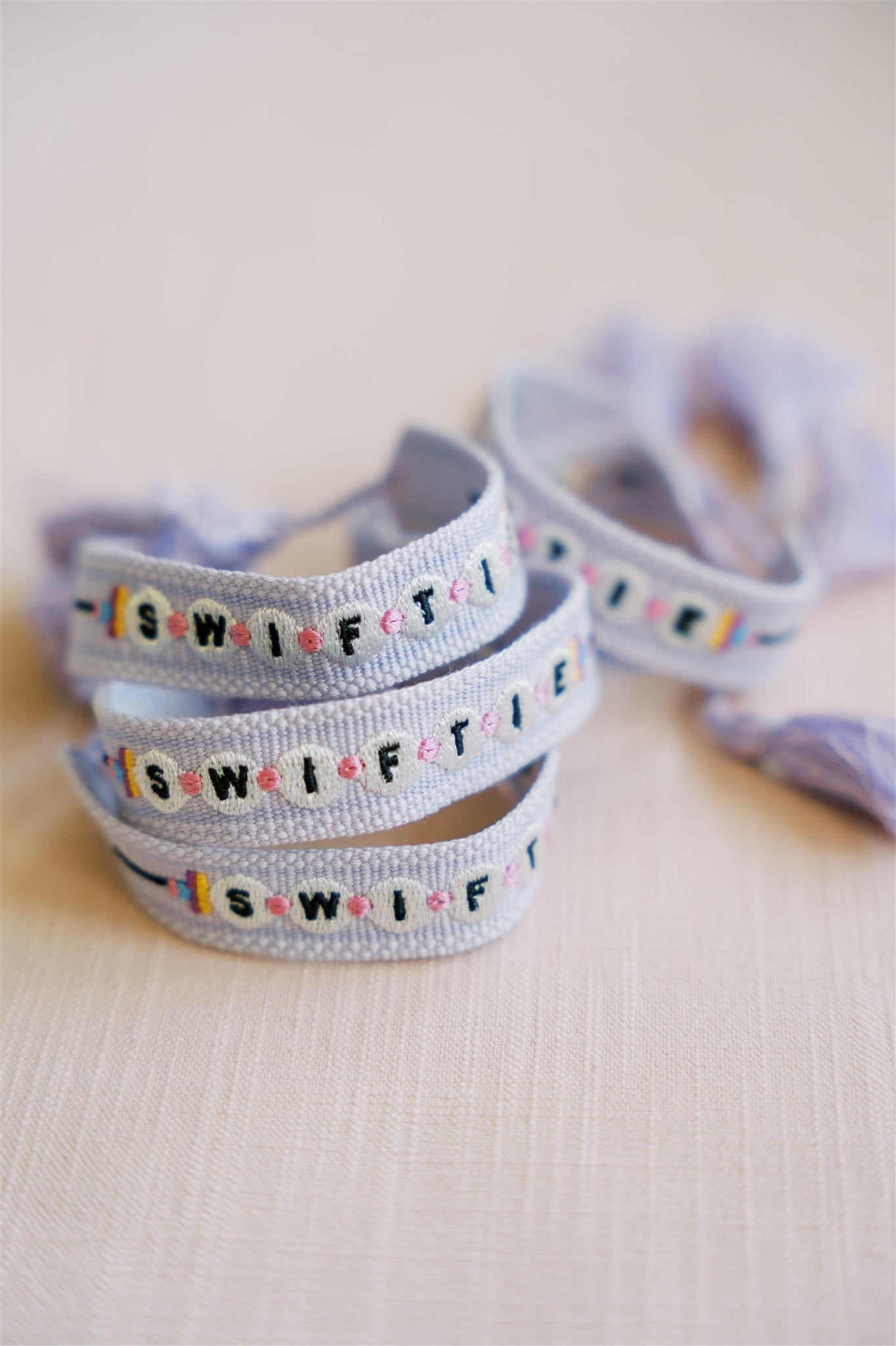 Light purple woven bracelet with "Swiftie" on it in a pattern that resembles beads.