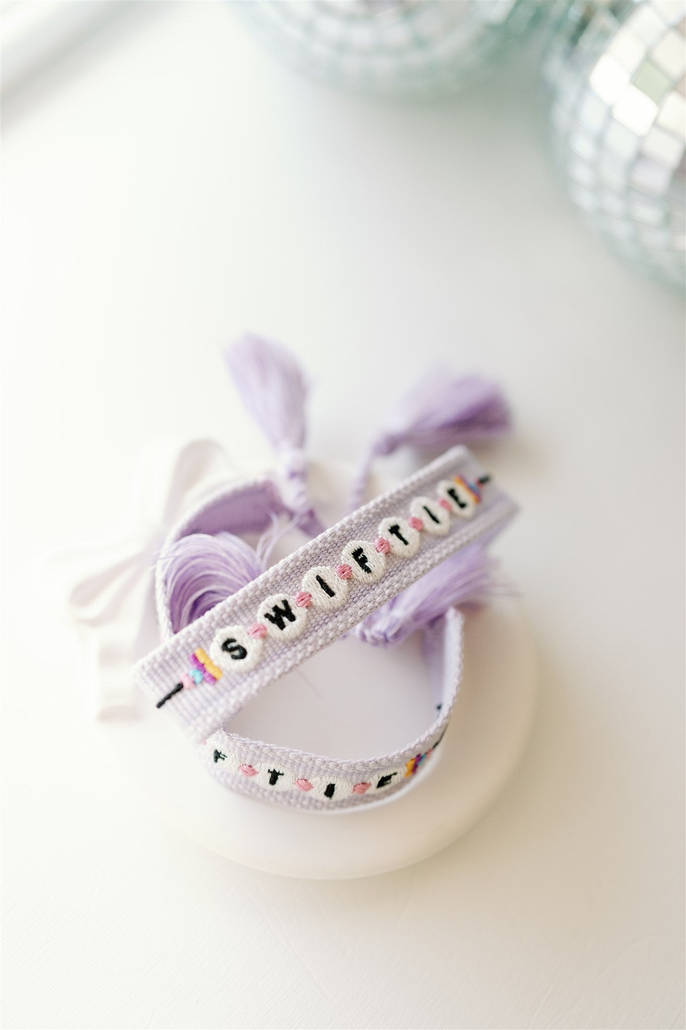 Light purple woven bracelet with "Swiftie" on it in a pattern that resembles beads.