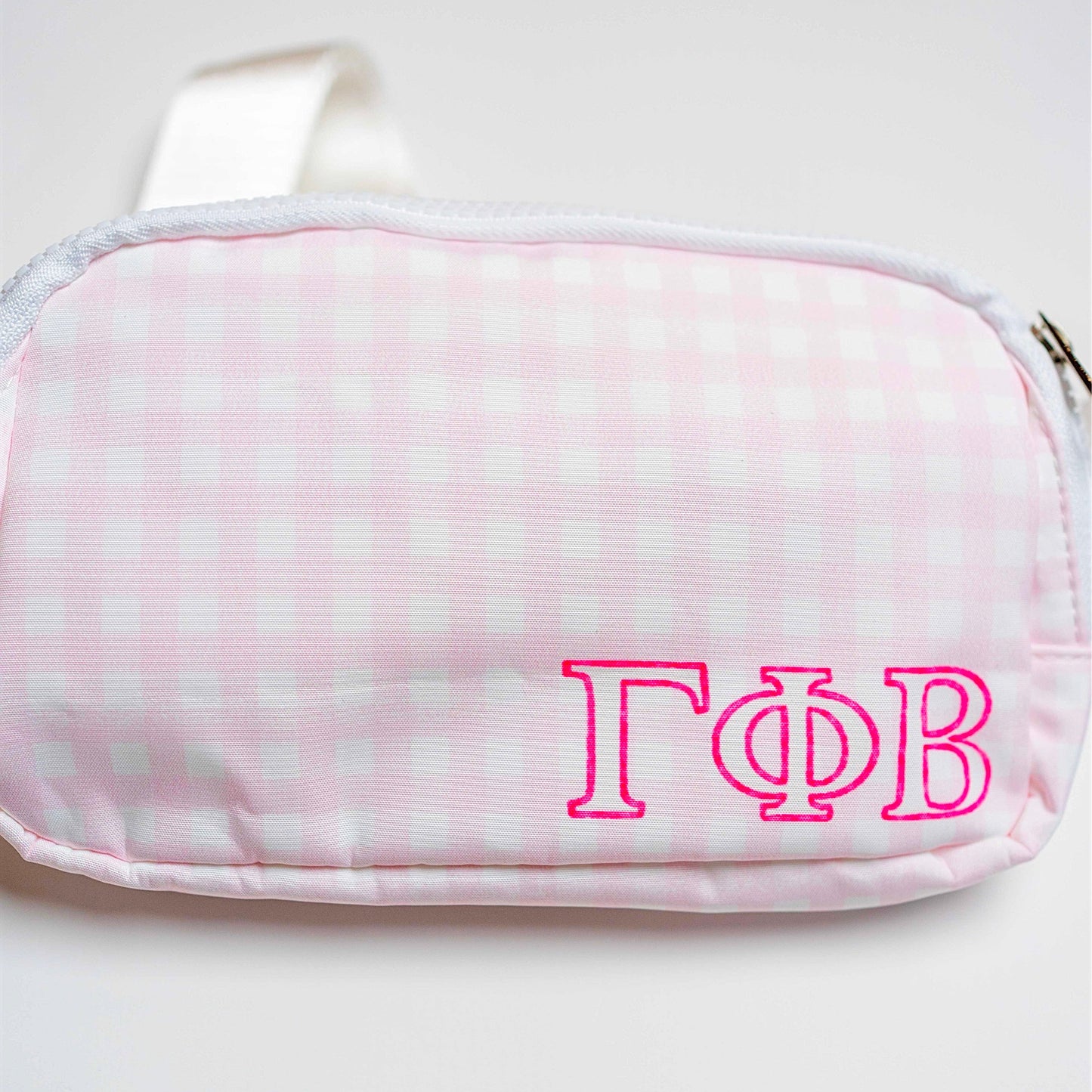 Pink and white checkered pouch with 'Gamma Phi Beta' letters on a white background