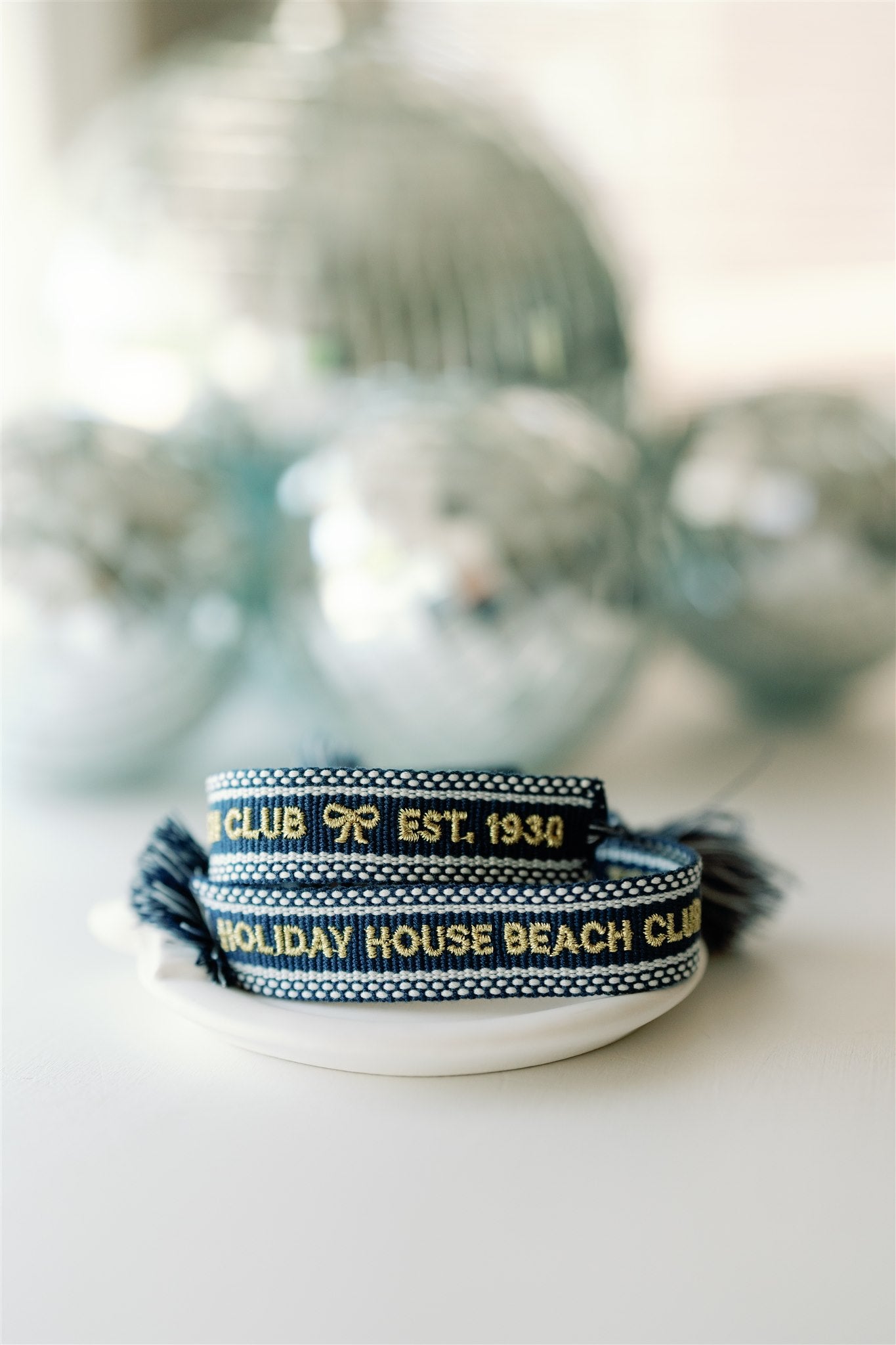 Navy blue woven bracelet with "Holiday House Beach Club est.1930" written on it in gold.