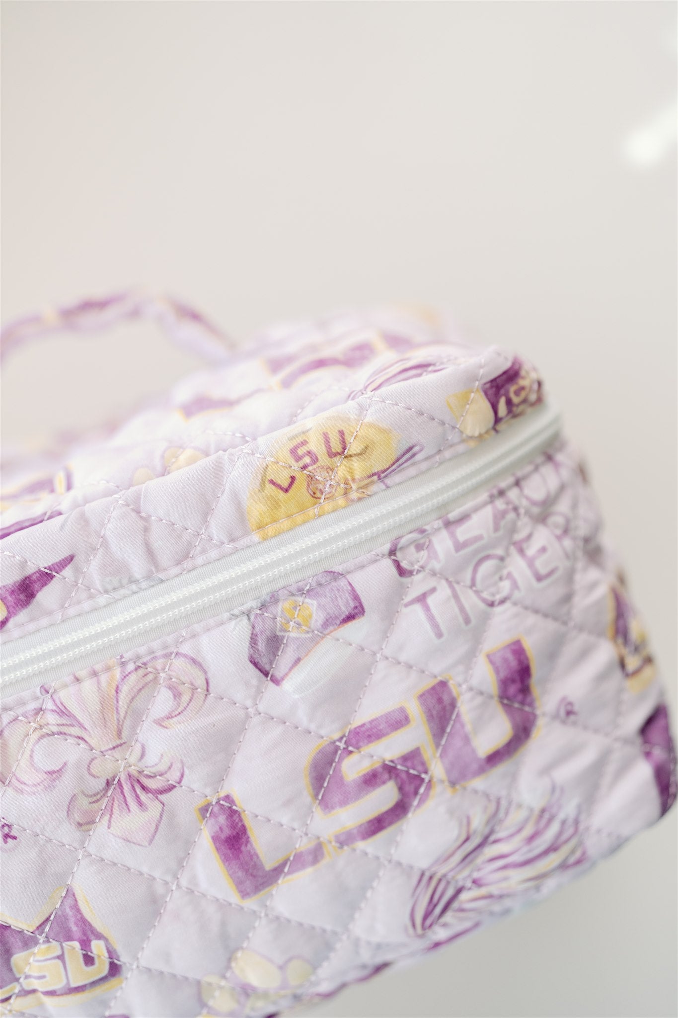 Light purple quilted make up bag with watercolor LSU symbols on it.