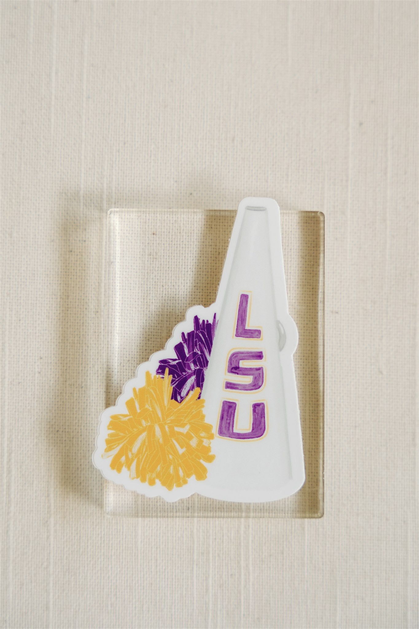 Sticker of a watercolor illustration of the LSU megaphone and a yellow and purple pom pom.