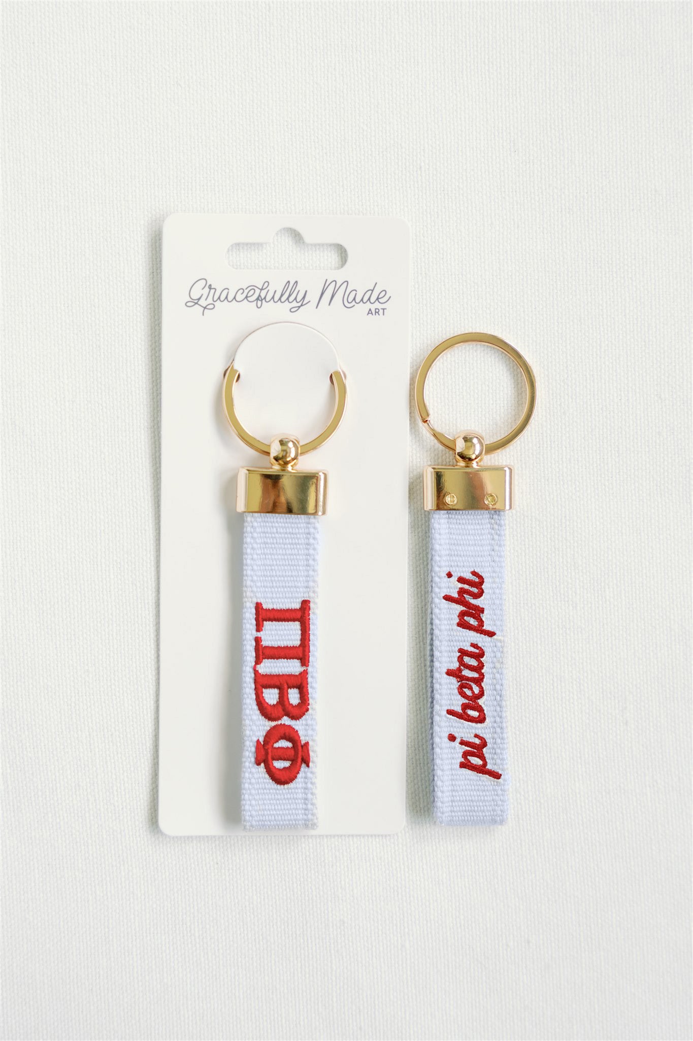 Front and back of the Pi Beta Phi embroidered keychain with Gracefully Made Art branded packaging.