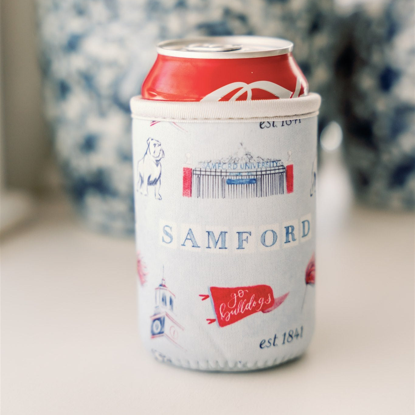 Light blue coffee sleeve with watercolor symbols themed to Samford University printed on it.