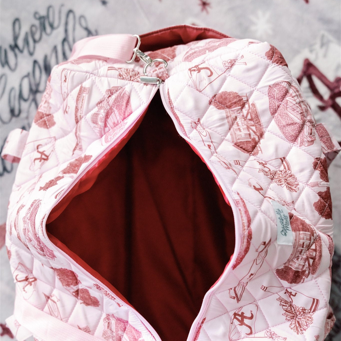 Light red quilted duffle bag with red University of Alabama symbols.