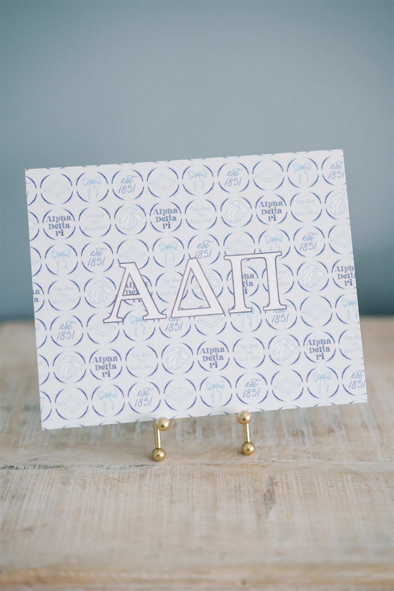Watercolor art print with 'Alpha Delta Pi' Greek letters on a stand against a gray background