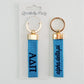 Front and back of blue Alpha Delta Pi keychains with gold rings on a white background, branded 'Gracefully Made Art'.