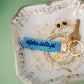Decorative jewelry dish with gold jewelry and an Alpha Delta Pi blue keychain.