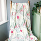 Floral Alpha Gamma Delta patterned blanket draped over a wooden chair against a blue wall.
