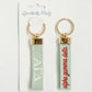 Front and back of Alpha Gamma Delta keychain with Gracefully Made Art branded packaging.