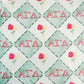Fabric with red 'Alpha Gamma Delta' letters and floral patterns on a green and white checkered background.