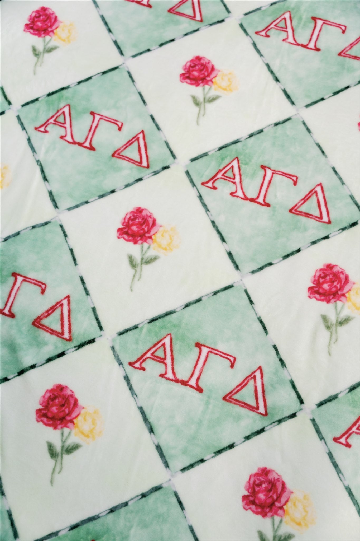 Pattern of 'ΑΓΔ' letters with red roses on a green background