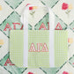Green checkered tote bag with white straps and Alpha Gamma Delta Greek letters with the flannel fleece blanket behind it.