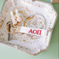 White keychain with red Alpha Omicron Pi Greek letters on a decorative dish.