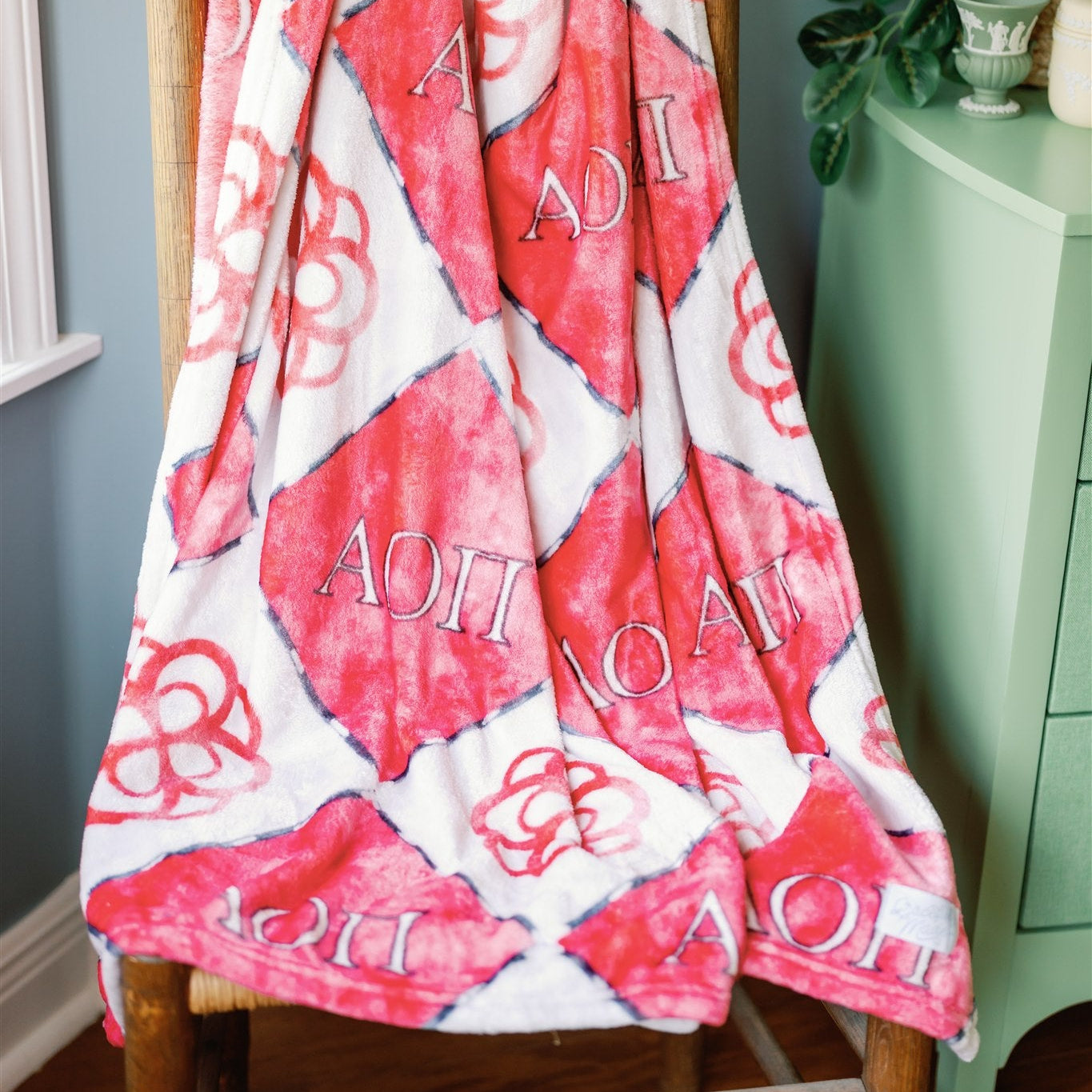 Red and gray patterned blanket with 'AOII' initials draped over a chair.