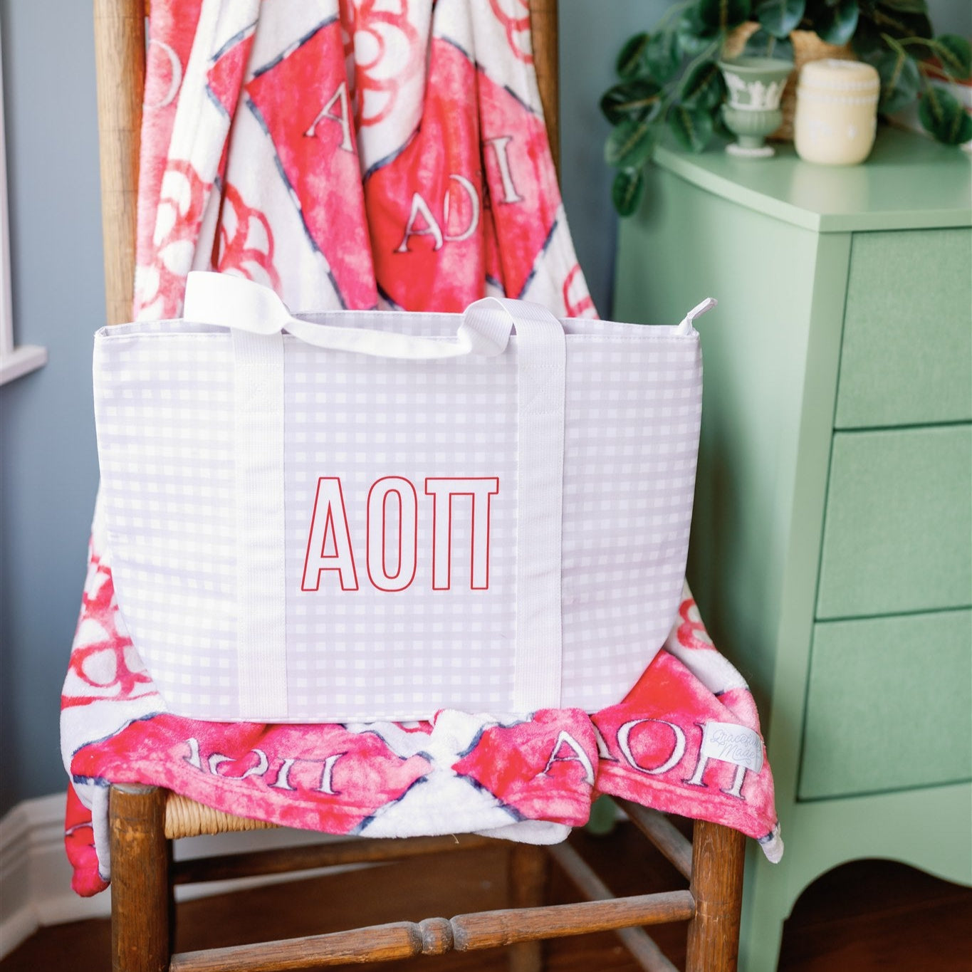 White and gray checkered tote bag with white straps and Alpha Omicron Pi Greek letters.