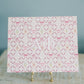 Decorative art print with 'Alpha Phi' Greek letters on a stand against a light blue background