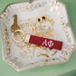 Decorative jewelry dish with a red keychain with Alpha Phi Greek letters embroidered on it.